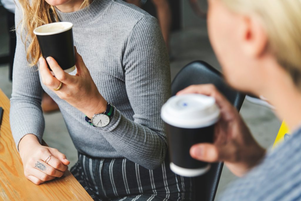 2 personnes qui parlent avec une tasse de café à la main
